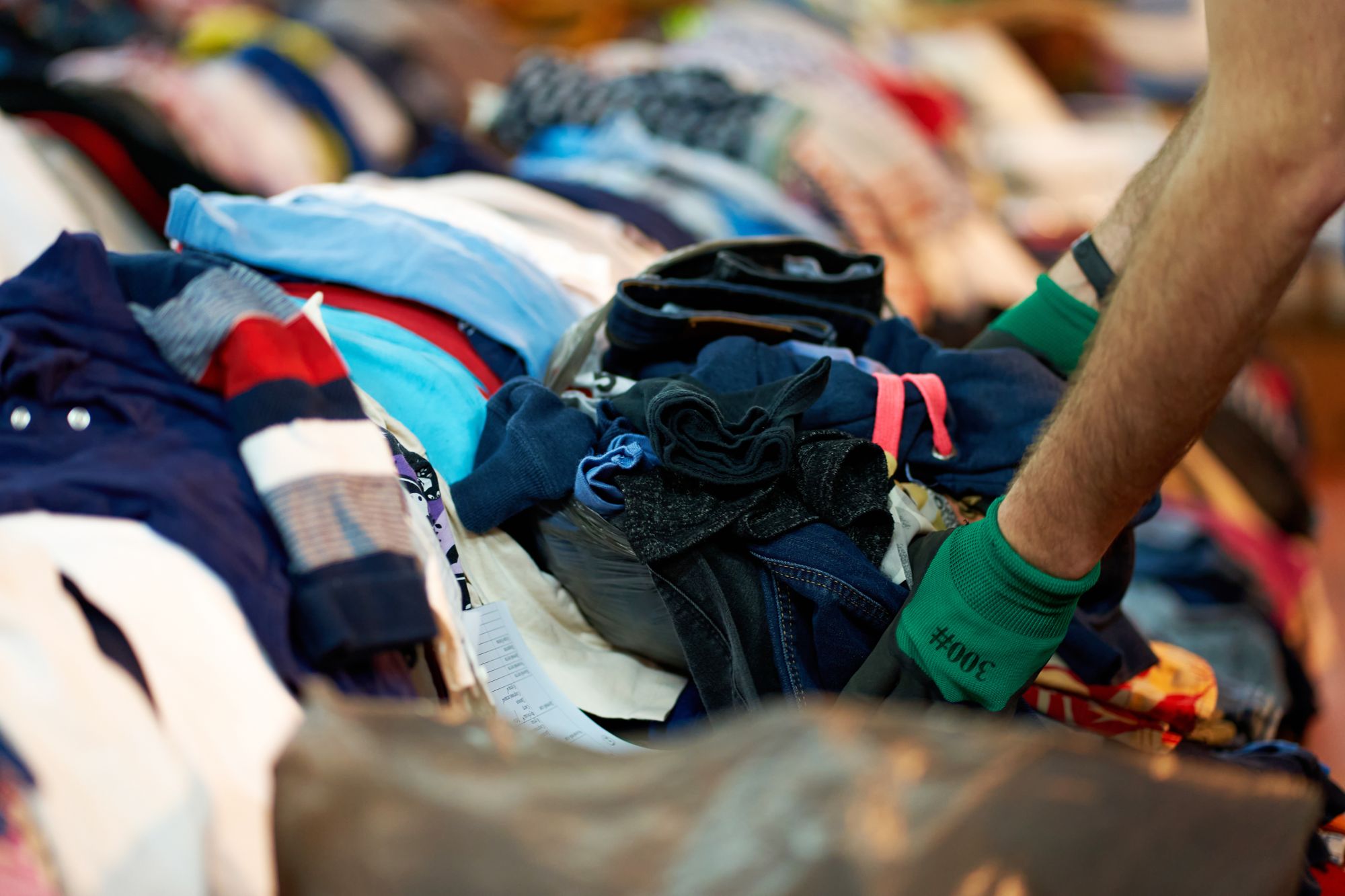 Gloved hands sorting a pile of used clothing